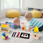 Dva dojenčka na preprogi ob lesenih Montessori senzoričnih igračah, del paketa MAXI 0–6 mesecev