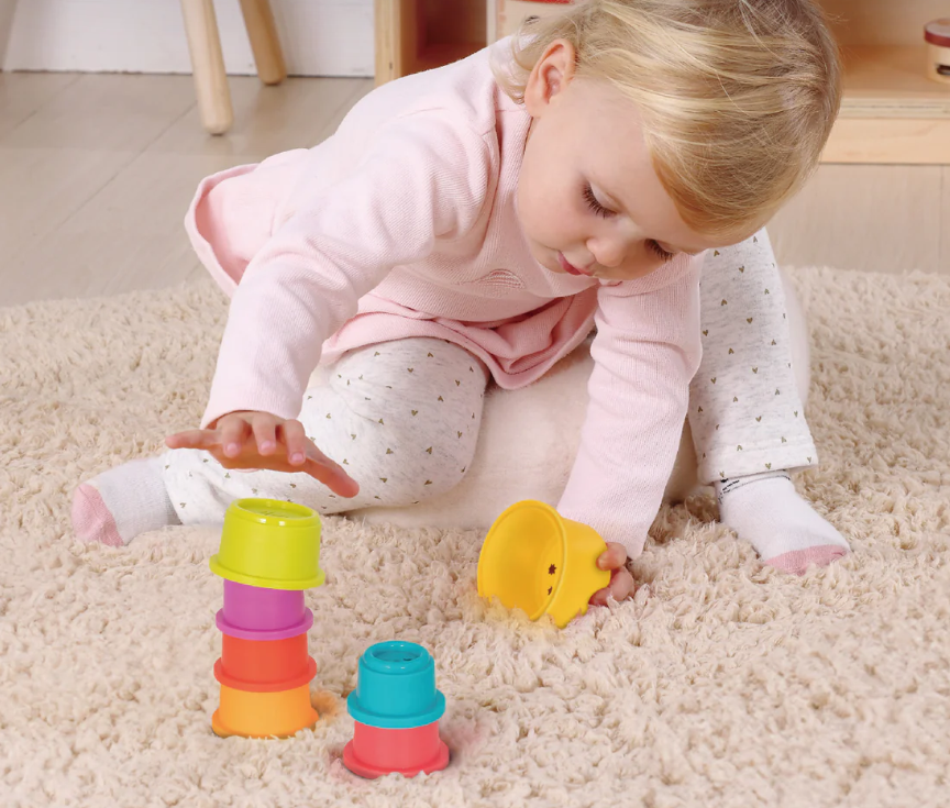 Malček se igra z barvnimi zlagalnimi skodelicami – lesene Montessori igrače za razvoj motorike, primerno za starost 13–18 mesecev (PAKET MAXI)